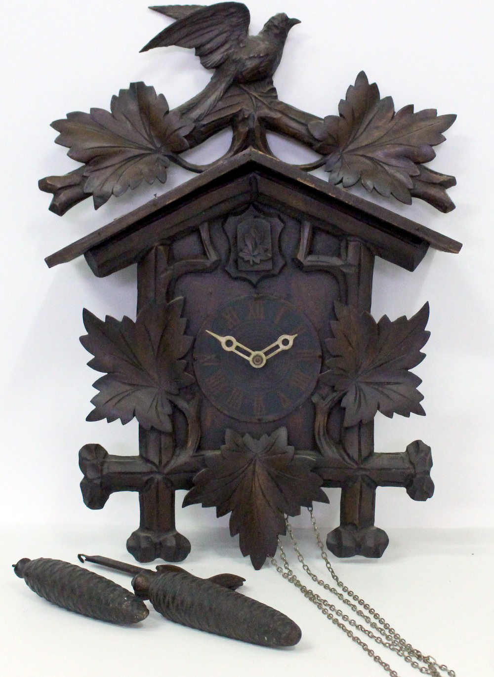 A 20TH CENTURY BLACK FOREST STYLE CARVED CUCKOO CLOCK with bird pediment, weights and pendulum,
