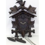 A 20TH CENTURY BLACK FOREST STYLE CARVED CUCKOO CLOCK with bird pediment, weights and pendulum,