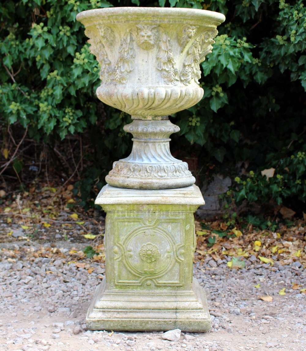 A RECONSTITUTED STONE OF CLASSICAL FORM decorated with masks and floral swags, 53cm diameter x 107cm