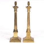 A PAIR OF 20TH CENTURY BRASS CORINTHIAN COLUMN TABLE LAMPS standing on square bases with gadrooned