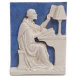 A BLUE AND WHITE POTTERY PLAQUE in the style of Della Robbia, depicting a monk copying text at a