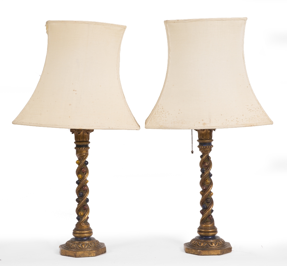 A PAIR OF CARVED PAINTED GILT WOOD AND POLYCHROME TABLE LAMPS of column form on spreading bases, the