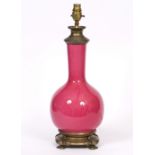 A PINK GLAZED POTTERY TABLE LAMP with brass mounts, of bottle form, by the Tingewick Pottery, signed