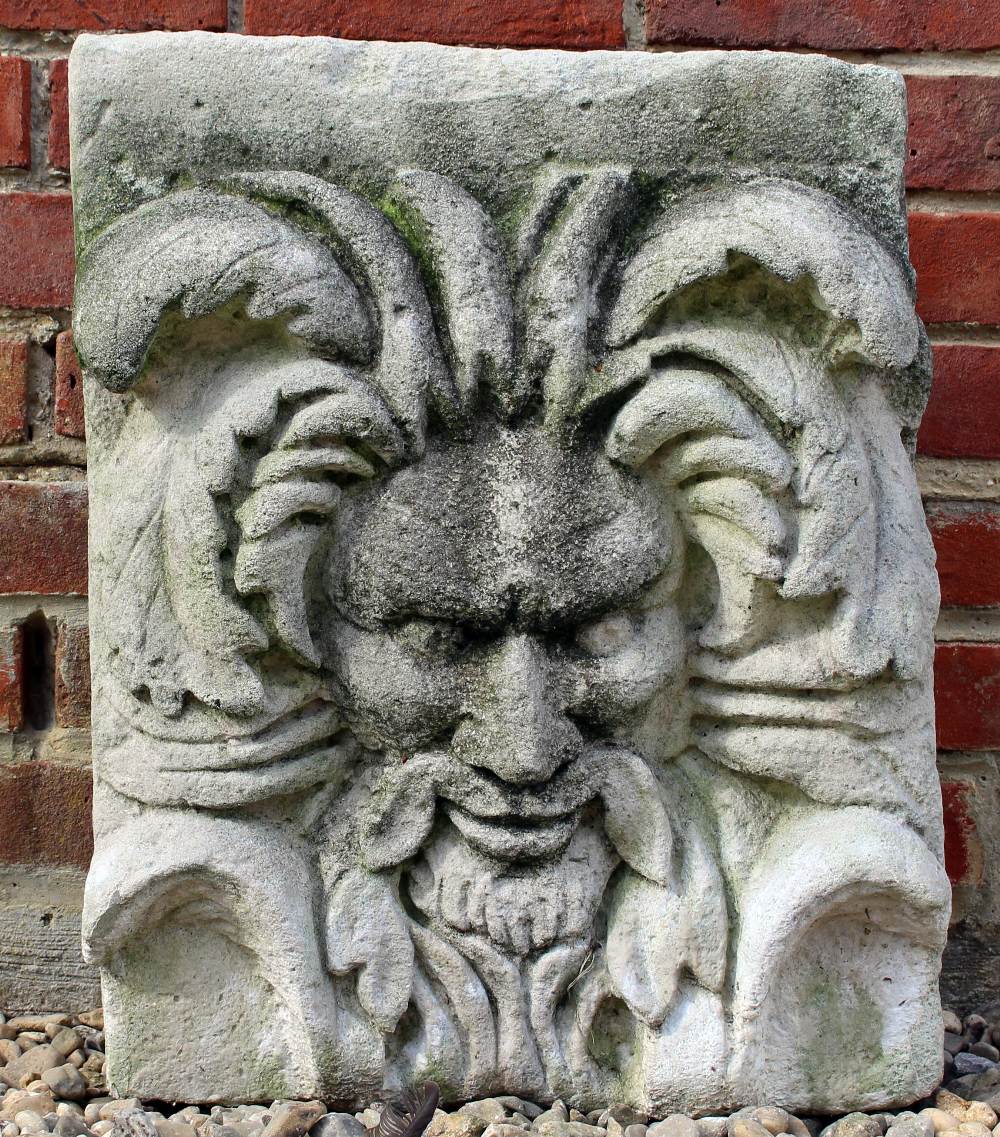 A CAST RECONSTITUTED STONE WALL PLAQUE depicting a wild man type mask, 43cm wide x 58cm high