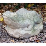 A CAST RECONSTITUTED STONE SCULPTURE of a frog resting on a rock 24cm wide x 36cm long x 21cm high