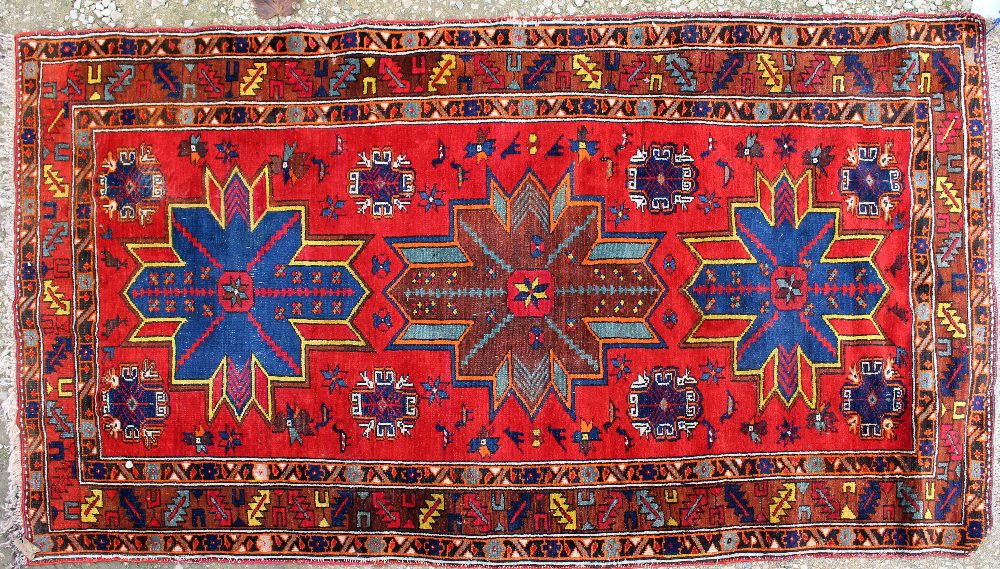 A RED GROUND RUG with three star motifs to the central field and within a triple banded border,