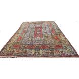 A RUG with over laid rectangular designs and stylised foliate bands, 377cm x 257cm (wear)