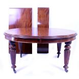 AN EARLY VICTORIAN MAHOGANY WIND OUT DINING TABLE with reeded legs terminating in brass and