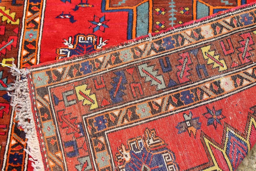 A RED GROUND RUG with three star motifs to the central field and within a triple banded border, - Image 2 of 2