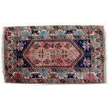 A TURKISH RED AND BLUE GROUND RUG with geometric decoration, 123cm x 207cm