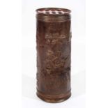 AN EMBOSSED COPPER CYLINDRICAL STICK STAND decorated with figures carousing in a tavern, 65cm high