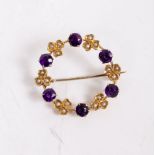 A YELLOW METAL AMETHYST COLOURED STONE AND SEED PEARL SET CIRCULAR BROOCH 2.2cm diameter