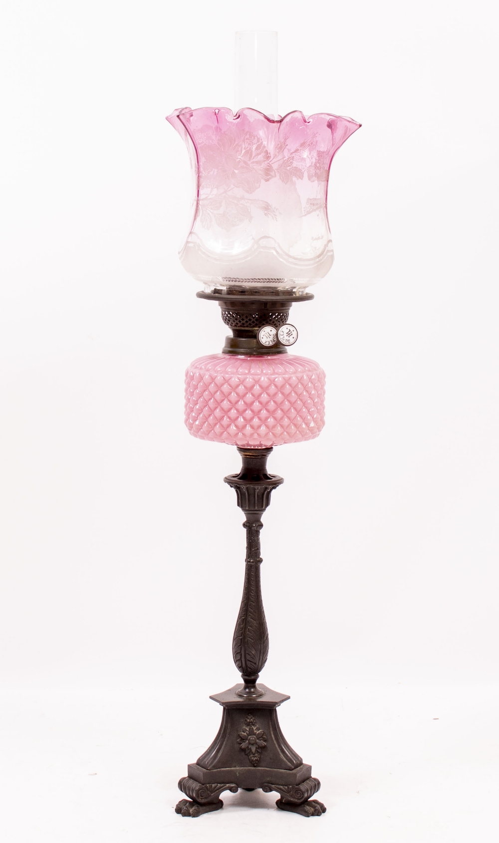 A LATE 19TH CENTURY BRONZE OIL LAMP with a cranberry glass shade, duplex burner, pink glass well and