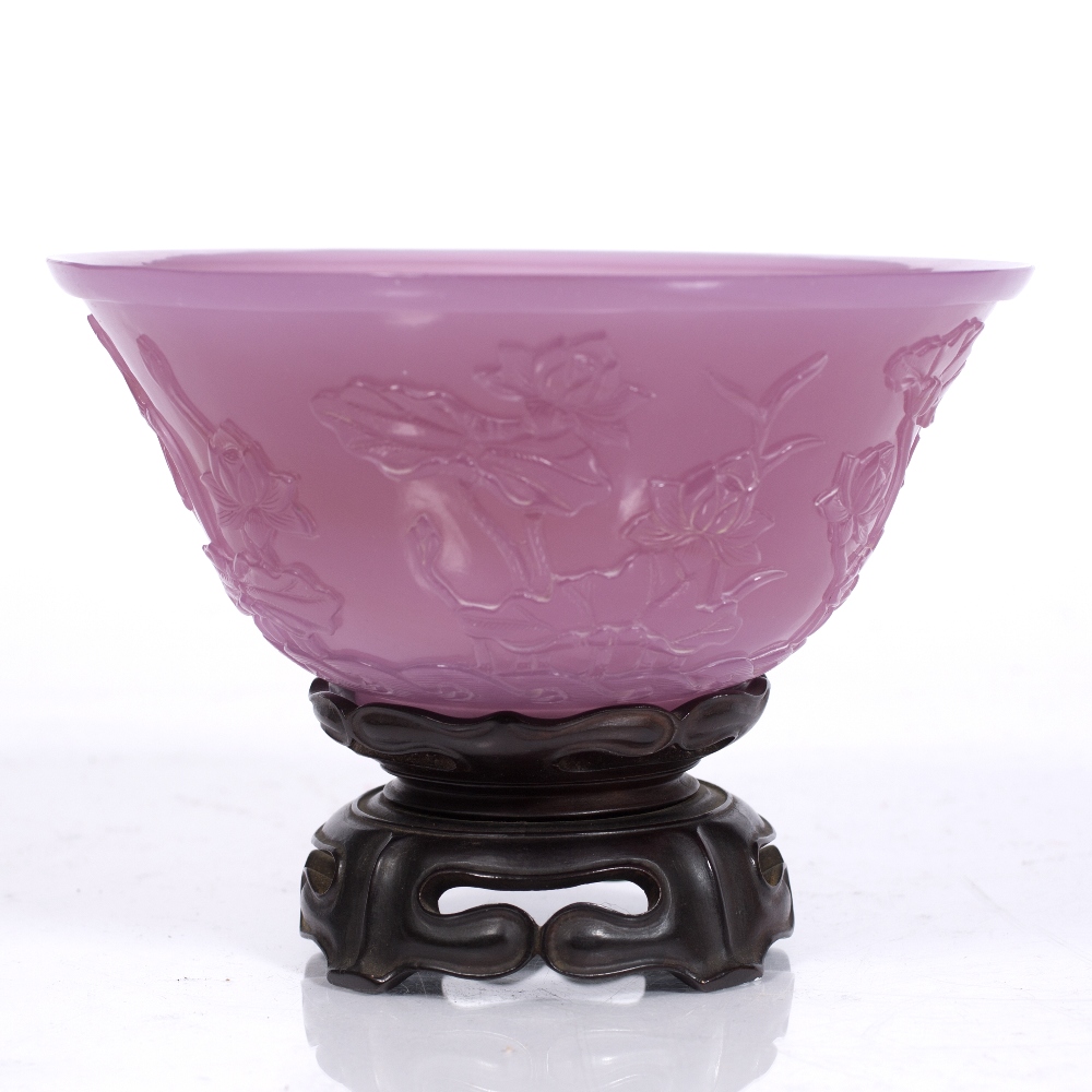 A Chinese Beijing translucent purple glass bowl decorated with lotus flower plants emerging from a