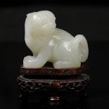 A Chinese pale green jade 19th Century seated Pekinese looking over left shoulder, pierced and