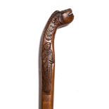 A Sri Lankan fruitwood walking stick 19th Century carved with a makara's head and parakeet, 89cm