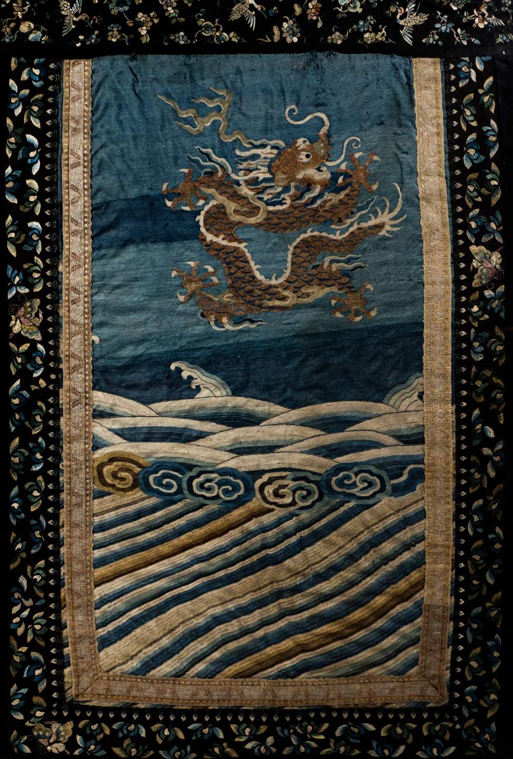 A Chinese textile panel 18th/19th Century embroidered with a five clawed dragon and celestial waves,