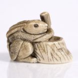 A Japanese ivory netsuke of a squatting rat early 20th Century pounding elixir of life in an hibachi