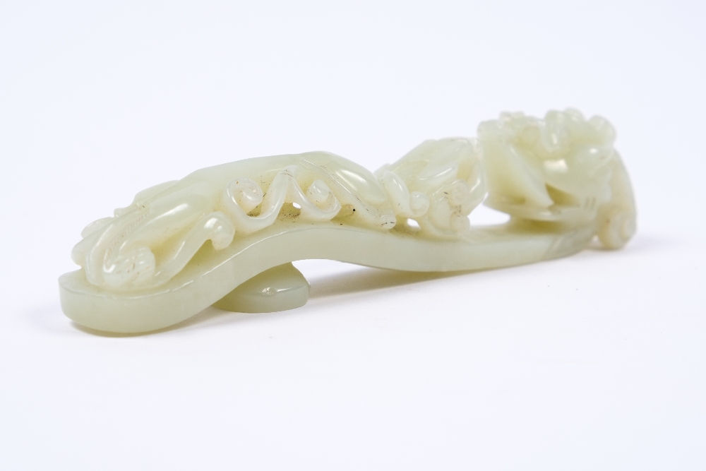 A Chinese white jade belt buck 19th Century with dragon headed hook and a sinuous pierced and carved
