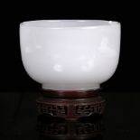 A Chinese Beijing glass bowl 19th Century imitating jade on a hardwood stand, 11cm across x 8cm high