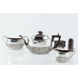 A LATE VICTORIAN SILVER THREE PIECE BACHELOR'S TEA SET, of half lobed design, the teapot with