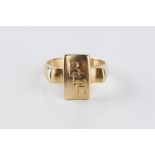 A YELLOW PRECIOUS METAL SIGNET RING, the shaped rectangular panel between square fluted shoulders,