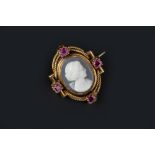 A HARDSTONE CAMEO AND RUBY BROOCH, the oval hardstone cameo carved to depict a female portrait