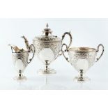 A LATE VICTORIAN SILVER PLATED THREE PIECE TEA SERVICE, of urn form, repoussé decorated and engraved