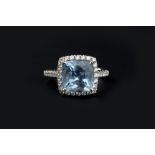 AN AQUAMARINE AND DIAMOND CLUSTER RING, the cushion-shaped mixed-cut aquamarine claw set within a