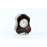 AN EARLY 20TH CENTURY SILVER MOUNTED TORTOISESHELL SMALL MANTEL TIMEPIECE, of shaped outline, with