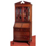 A GEORGIAN STYLE MAHOGANY BUREAU BOOKCASE, the broken arched pediment over glazed doors, fall