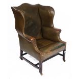 A GEORGE III MAHOGANY FRAME WING ARMCHAIR upholstered in brass studded green leather on chamfered