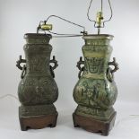 A pair of Chinese bronzed table lamps, on stands,