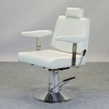 A white leather upholstered barber's chair on a chrome base