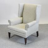 An Edwardian cream upholstered wing back armchair,