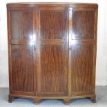 An Edwardian mahogany bow front triple wardrobe,