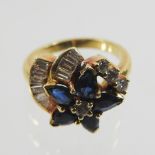An 18 carat gold sapphire and diamond cluster ring, of asymmetrical design,