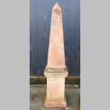 A terracotta garden obelisk, on a matching pedestal,