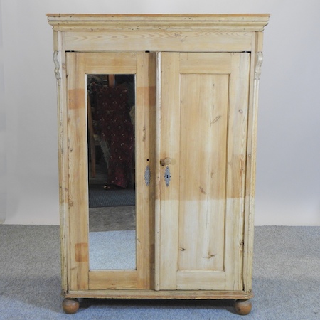 An antique pine double wardrobe with a mirrored door,