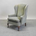 A 1920's green upholstered wing back armchair,