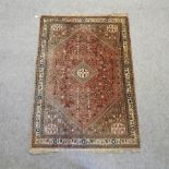 A Persian woollen rug, with a central medallion and flowers, birds and animals, on a red ground,