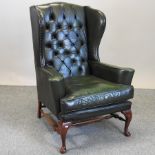 A modern green upholstered wing back armchair