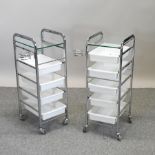 A pair of chrome trolleys, each with a glass top,