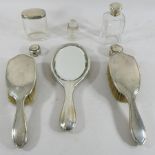 A silver dressing table set comprising of a mirror and two brushes,