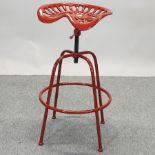 A red painted cast iron tractor seat bar stool