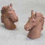 A pair of rusted cast iron models of horse heads,