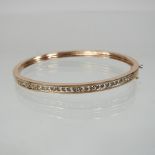 A 9 carat gold and diamond bangle, of hinged design,
