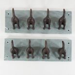 Two sets of hooks in the form of dog's tails, each mounted on slate,