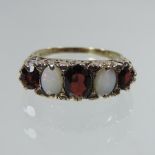 An 18 carat gold opal, garnet and diamond ring, with scrolled decoration,