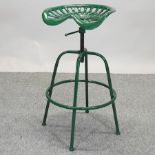 A green painted cast iron tractor seat bar stool